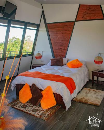 - une chambre avec un grand lit et des oreillers orange dans l'établissement Glamping LaMoro, à Sevilla