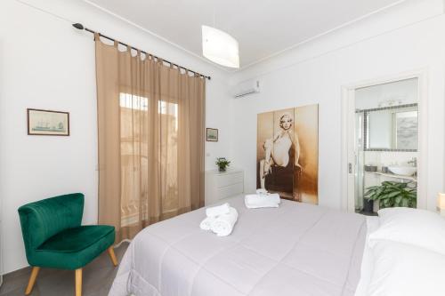 a white bedroom with a green chair and a bed at Casa Leucosia in Capri