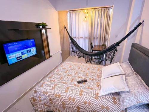 a hammock in a room with a bed and a television at Ap standard confort bem localizado in Campina Grande