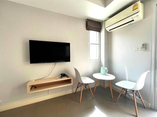 a living room with two chairs and a tv on a wall at Mitr Inn Mrt Samyot Station - The Grand Palace in Bangkok