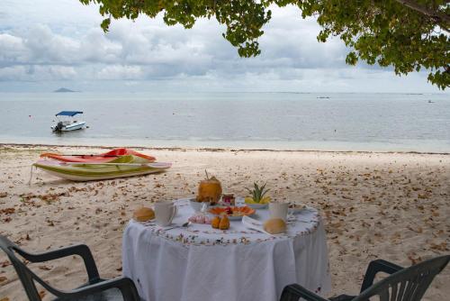 a table with food on the beach with a boat at La Case Creole in Roches Noires