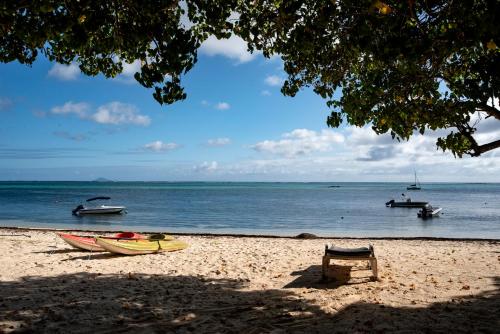 a beach with a bench and boats in the water at La Case Creole in Roches Noires