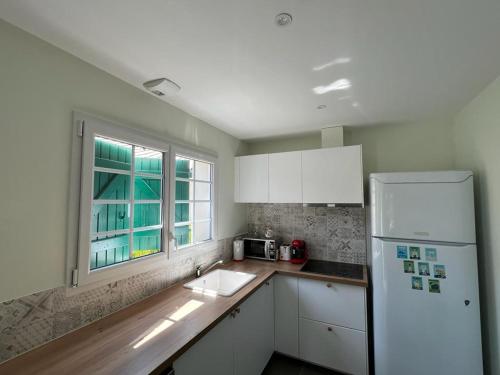 une cuisine avec un réfrigérateur blanc et une fenêtre dans l'établissement Studio à 10 minutes de l'océan, à Saint-André-de-Seignanx