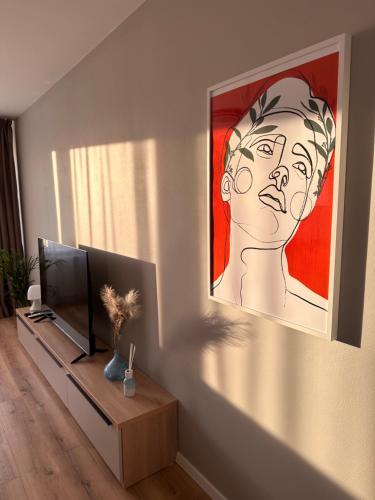 a living room with a television and a painting on the wall at Trendy Apartment in Trenčín