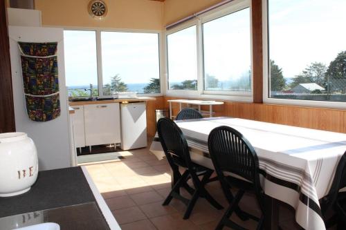 une cuisine avec une table, des chaises et des fenêtres dans l'établissement 756 - Chalet à Erquy avec vue mer à 200m de la plage et de l'îlot Saint Michel, à Beaumont