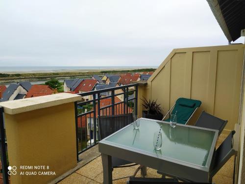 une table en verre sur un balcon avec une chaise dans l'établissement DIVINE MARINA vue mer - Piscines, à Dives-sur-Mer