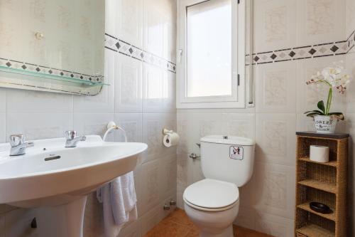 a white bathroom with a toilet and a sink at Villa Sol in Sant Cebrià de Vallalta