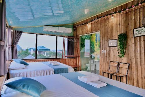 um quarto com 2 camas e uma grande janela em Hang Mua Bamboo Homestay Ninh Binh em Ninh Binh
