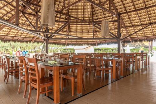 ein Restaurant mit Holztischen und -stühlen in einem Gebäude in der Unterkunft Vila Galé Fortaleza in Fortaleza