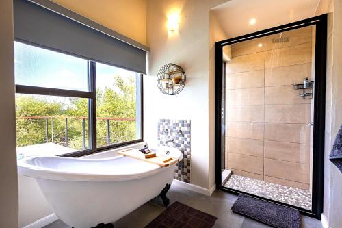 a bathroom with a large tub and a shower at Ndlovu Bushvilla in Mica