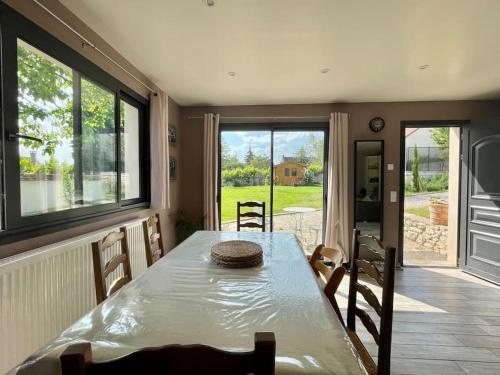 d'une salle à manger avec une table et quelques fenêtres. dans l'établissement Maison pleine de charme, à Dammartin-en-Serve