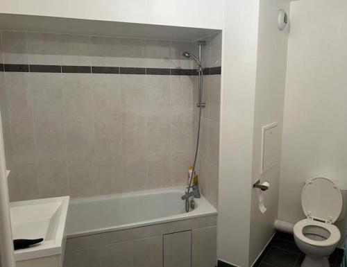 a bathroom with a tub and a toilet and a sink at Duplex avec vue sur la Tour Eiffel in Nanterre