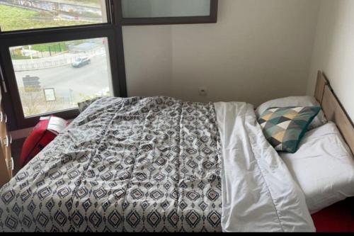 a bedroom with a bed with a comforter and a window at Duplex avec vue sur la Tour Eiffel in Nanterre