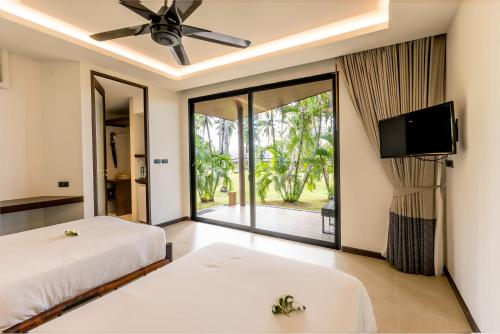 a bedroom with two beds and a flat screen tv at Phukhaolak Resort in Khao Lak