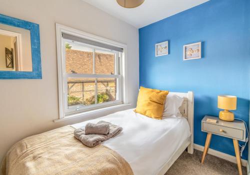 a blue bedroom with a bed and a window at 2 BR Stylish Bright Cottage, Pet Friendly - Titchfield Village by Blue Puffin Stays in Titchfield
