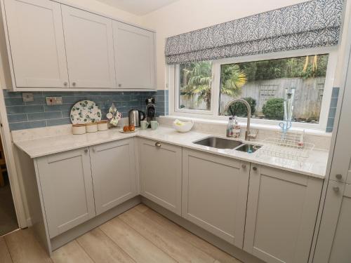 Una cocina con gabinetes blancos y un fregadero y una ventana. en Altair, en Freshwater