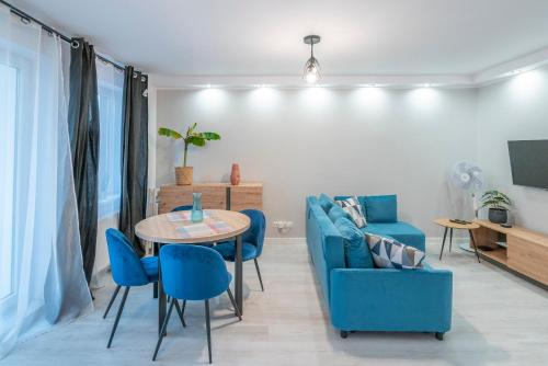 een woonkamer met een blauwe bank en een tafel en stoelen bij Stylowy apartament Blue ~self check in 24h in Wrocław