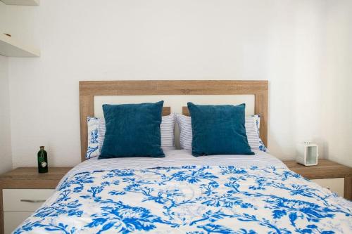 un letto con lenzuola bianche e blu e cuscini blu di Wonderful apartment in Gavà. Barcelona a Gavà