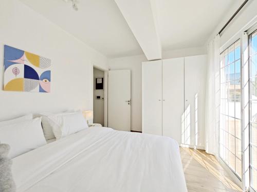 a white bedroom with a bed and a large window at Andromaches by Verde Apartments in Athens