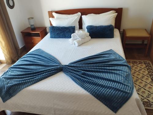 a bed with a blue bow tie on it at Casa Sarguito in Sagres