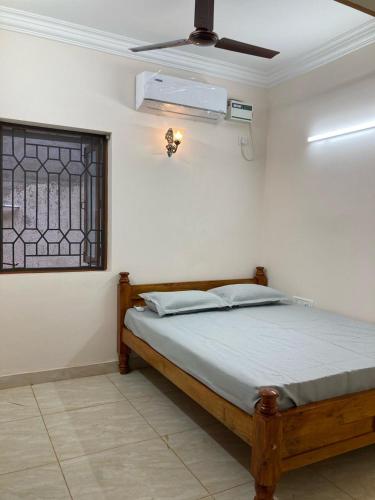 1 dormitorio con 1 cama, ventana y ventilador en Teynampet Eldams Road en Chennai