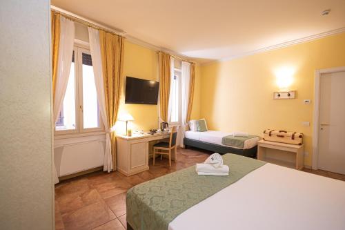 a bedroom with a bed and a desk and a television at Hotel Belvedere San Gottardo by LVG Hotel Collection in Verbania