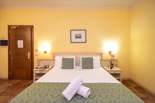 a bedroom with a large bed with two towels on it at Hotel Belvedere San Gottardo by LVG Hotel Collection in Verbania