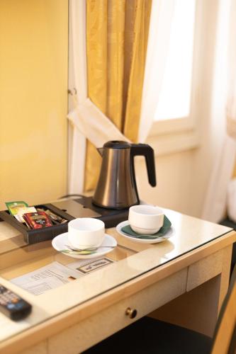 a coffee pot and two cups on a table at Hotel Belvedere San Gottardo by LVG Hotel Collection in Verbania
