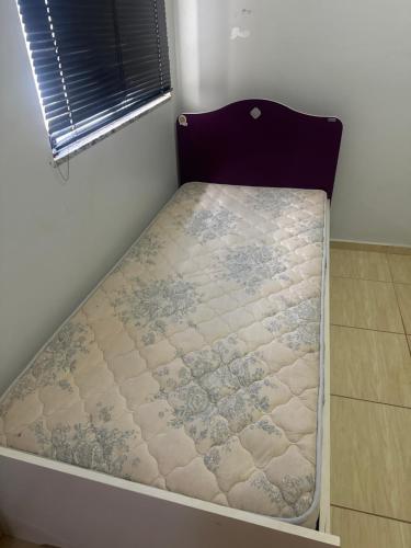 een klein bed in een kamer met een raam bij Casa da Denize in Cascavel