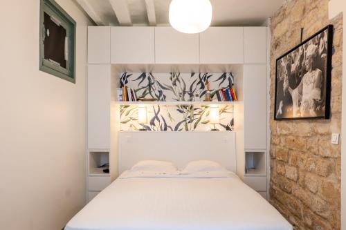 une chambre avec un lit blanc et un mur de briques dans l'établissement Veeve - A Story in Stone, à Paris