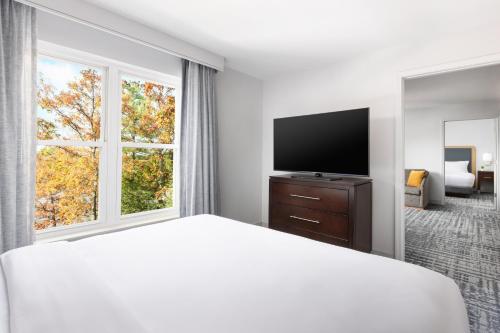 a hotel room with a bed and a flat screen tv at Homewood Suites by Hilton Manchester/Airport in Manchester