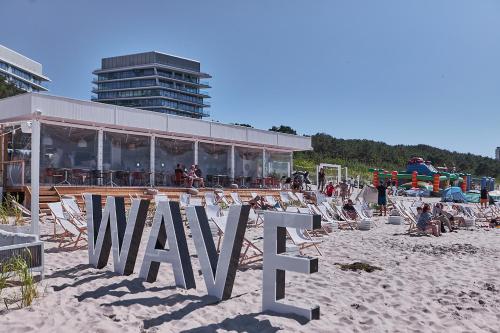a sign on a beach with chairs and a building at Wave De Luxe Studio Resort&SPA 755B - Sea View in Międzyzdroje