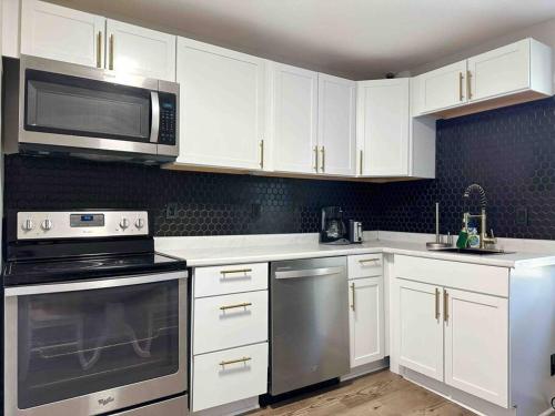 una cocina con armarios blancos y electrodomésticos de acero inoxidable en Rotherwood Roost / 2BR/1BA Apartment near UE, en Evansville