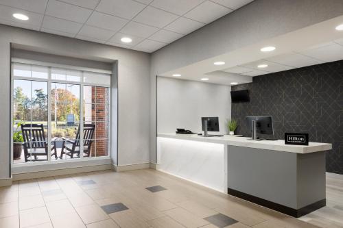 an office with a reception desk with a table and a window at Homewood Suites by Hilton Manchester/Airport in Manchester