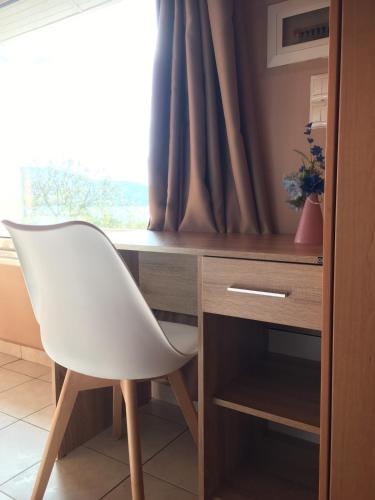 a white chair sitting next to a desk with a window at Penthouse Studio next to the Sea in Salamís