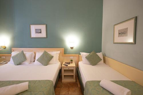 a hotel room with two beds and a table at Hotel Belvedere San Gottardo by LVG Hotel Collection in Verbania