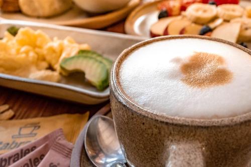 a cup of coffee sitting next to a plate of food at Carilo Hills by bund in Carilo