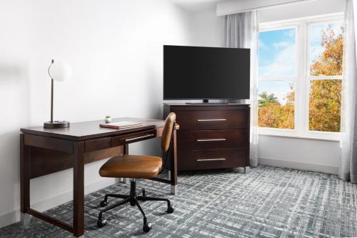 a room with a desk with a television and a chair at Homewood Suites by Hilton Manchester/Airport in Manchester