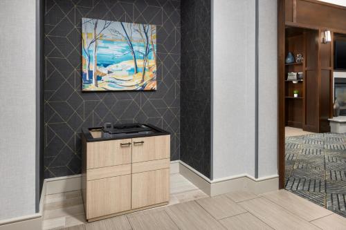 a kitchen with a cabinet and a painting on the wall at Homewood Suites by Hilton Manchester/Airport in Manchester