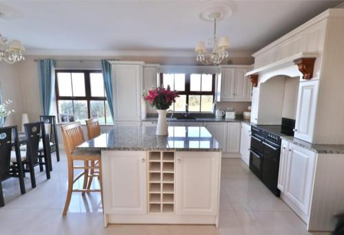 a kitchen with white cabinets and a table with flowers on it at The Cliffs of Moher Holiday House in Doolin