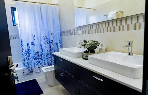 a bathroom with a white sink and a blue shower curtain at Ochi Rios Palace Vacation Home in Falmouth