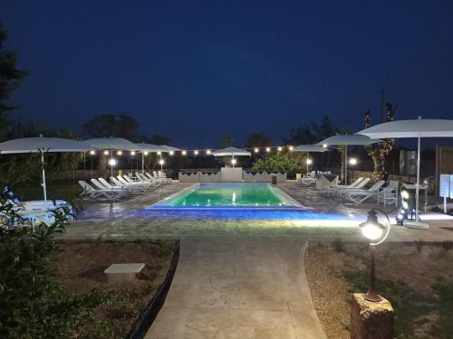 a swimming pool with chairs and umbrellas at night at B&b Casina Il Mandorlo in Nardò