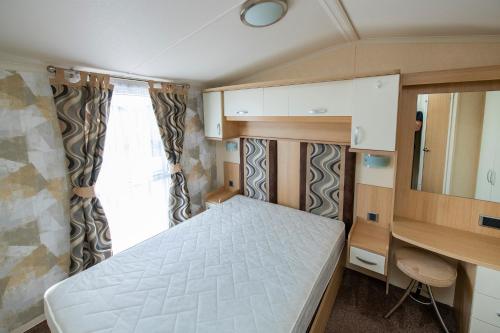 Habitación pequeña con cama y escritorio. en Camping Marina Nowe Guty, en Nowe Guty