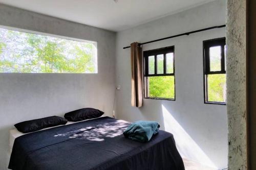 a bedroom with a bed and two windows at Casa de Campo Diamantina MG in Diamantina