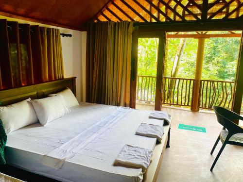 um quarto com uma cama grande e uma varanda em The Rainforest Hideaway em Deniyaya