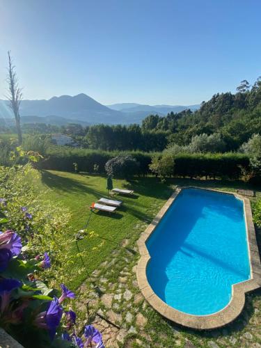 a pool in a garden with mountains in the background at Turra Nature House in Celorico de Basto