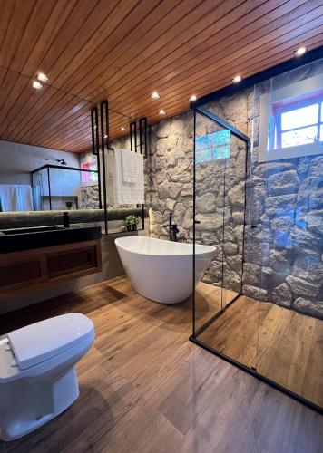 a bathroom with a tub and a toilet and a shower at Pousada Boutique Villa Chafariz Tiradentes in Tiradentes