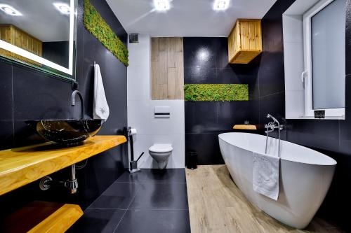 a bathroom with a large white tub and a toilet at Apartamenty czarna perła in Szaflary