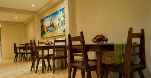 uma sala de jantar com mesas e cadeiras de madeira e um quadro em Hotel y Bungalows Santa Ana em Quetzaltenango