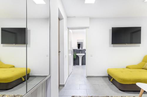 a living room with yellow furniture and a tv at Bada Bing Residence in Braşov